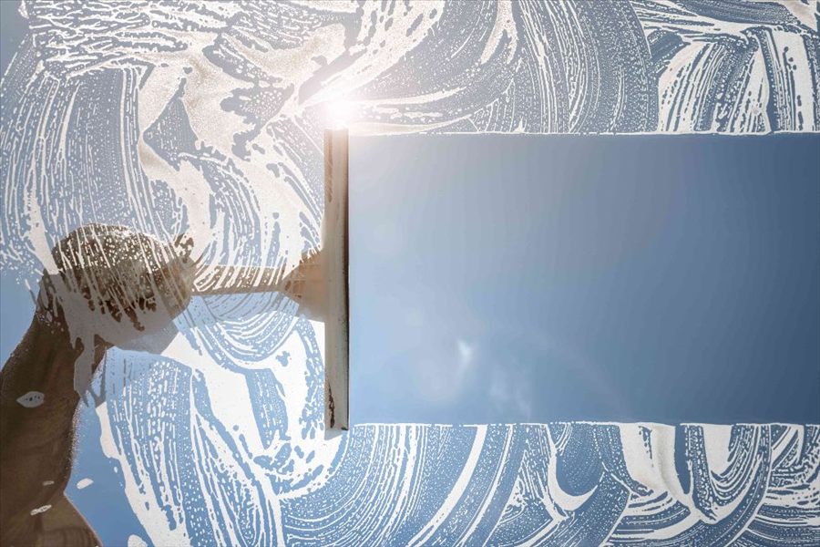 A squeegee clearing soapy water from a window